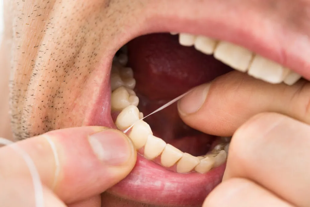A focused shot of a man flossing his teeth using a dental floss