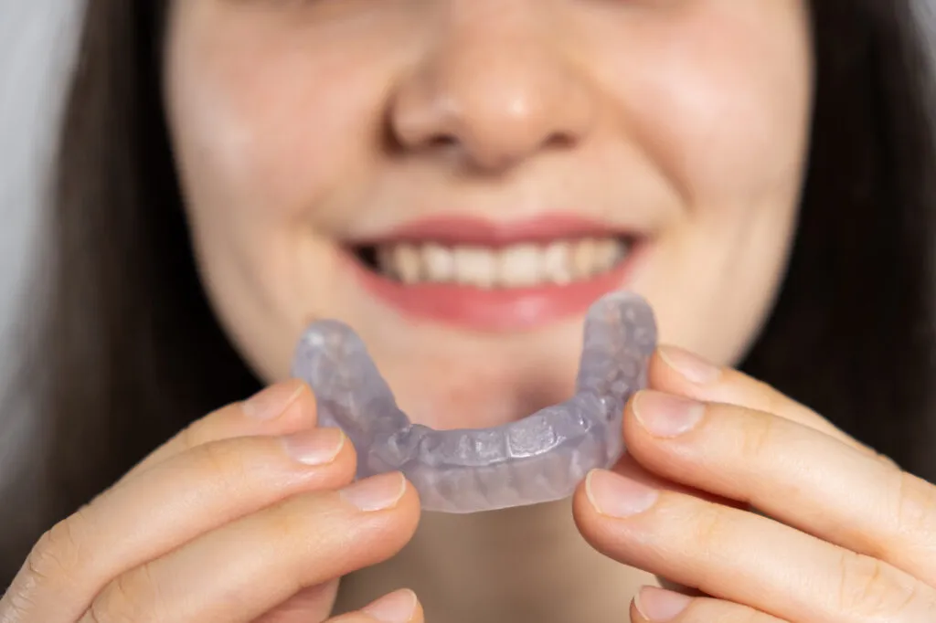 A woman holds dental mouthguard to treat her sleep apnea