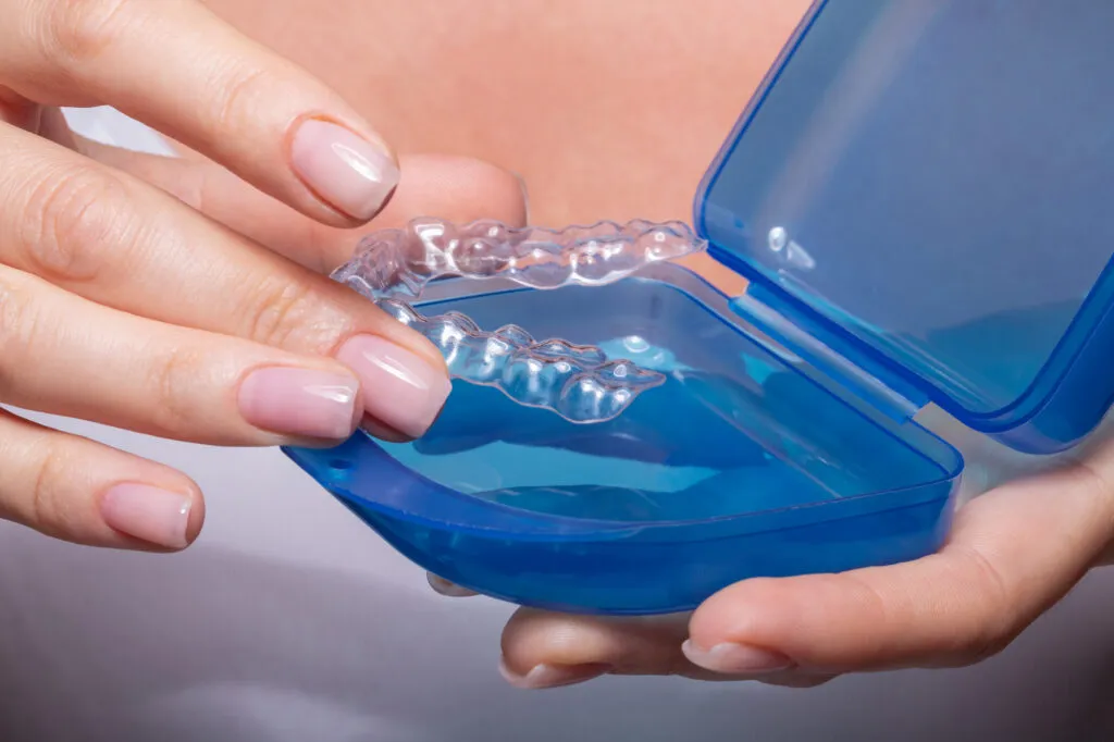 Cropped shot of a womans Hand Putting Transparent Night Time Aligner In Blue Case