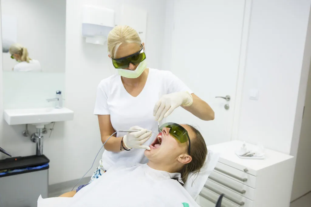 Dental hygienist using diode laser on a patient for orthodontic treatment
