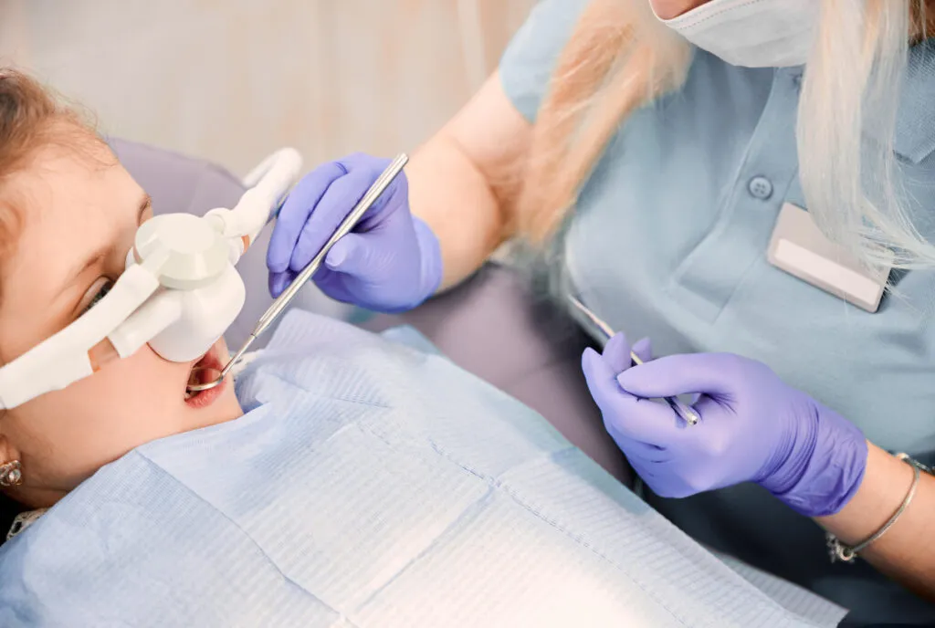 Dentist administering a gask mask or laughing gas on a young girl patient