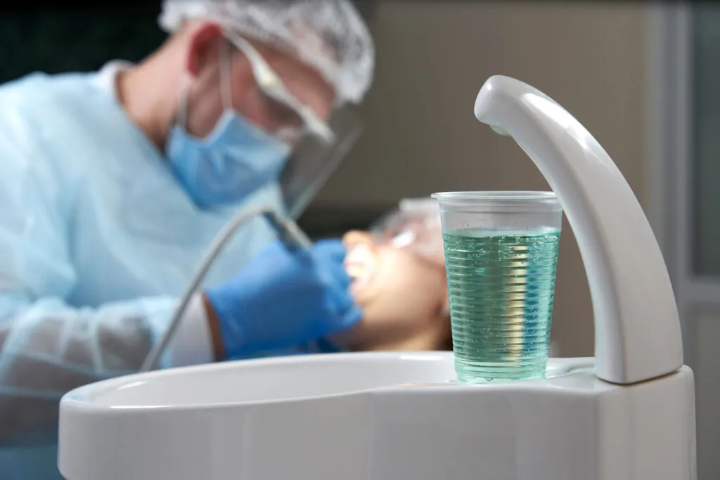 Dentist doing a dental treatment on a female patient with a focus on the saline solution as mouthwash