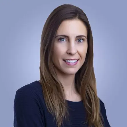Dr. Jennifer Silver, a dentist with long brown hair, smiling in a navy sweater against a blue-gray background