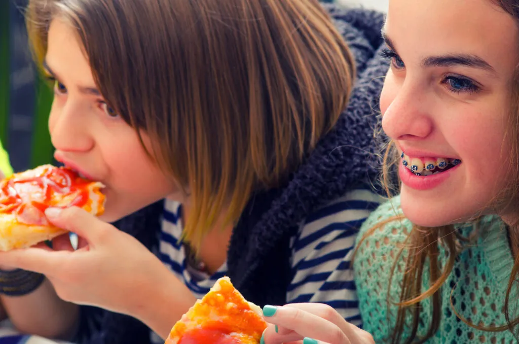 Teenage girls eating pizza with a focus on the girl with the braces