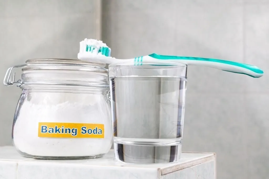 Baking soda beside glass of water with toothbrush on top