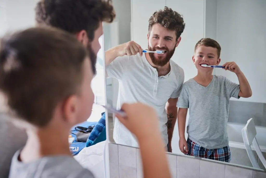 Dad and son brushing teeth in bathroom