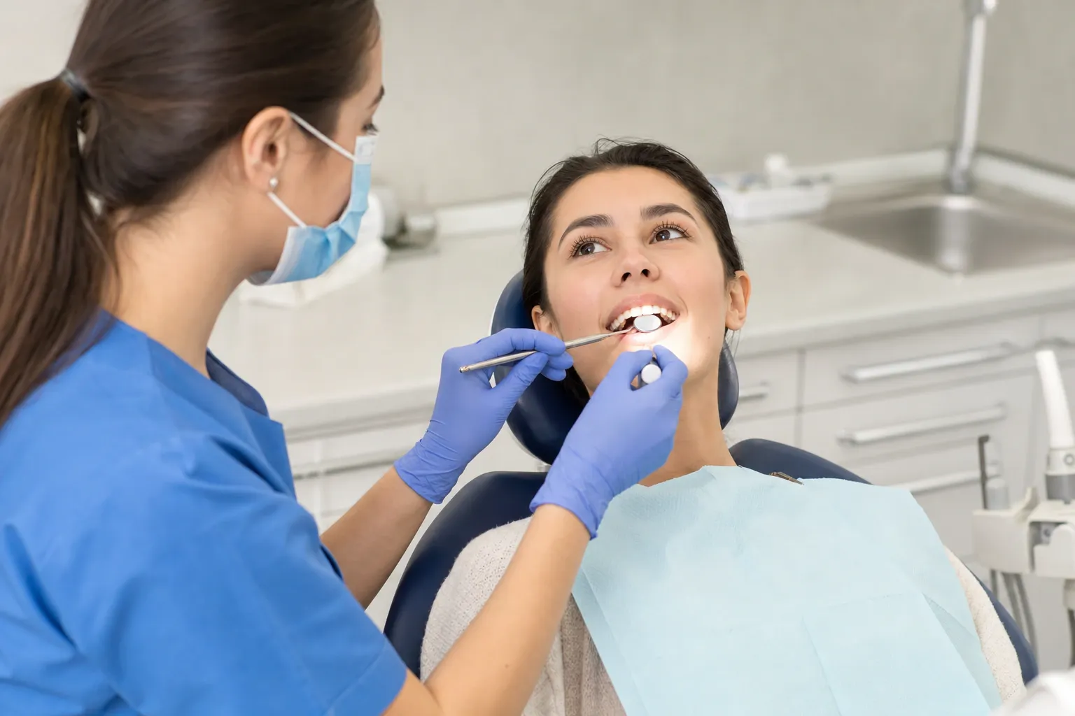 Dentists assistant examining teeth of patient 1 nm 0699