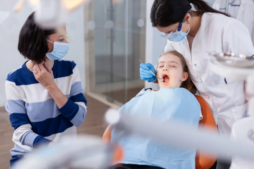 Mother watching daughter getting her teeth checked