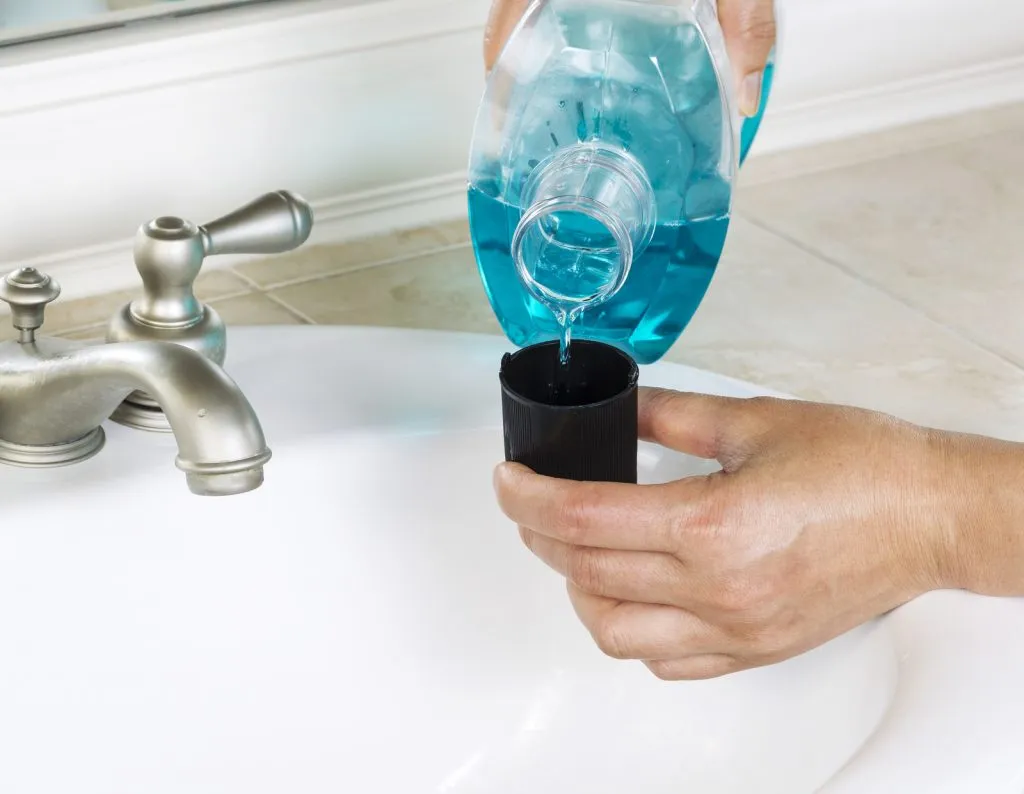 Person pouring mouthwash into cap