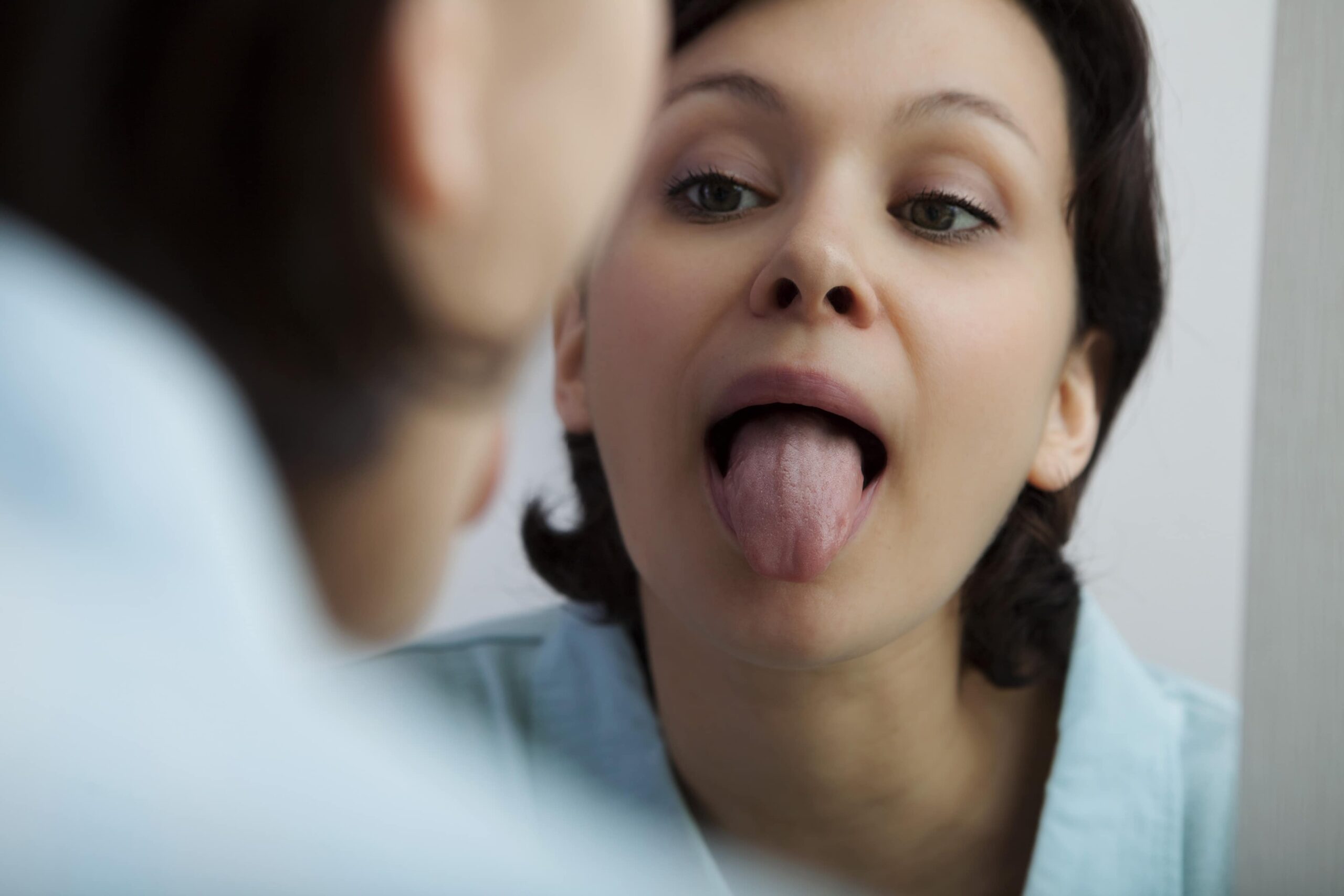 Person looking at their reflection in a mirror, sticking out their tongue.