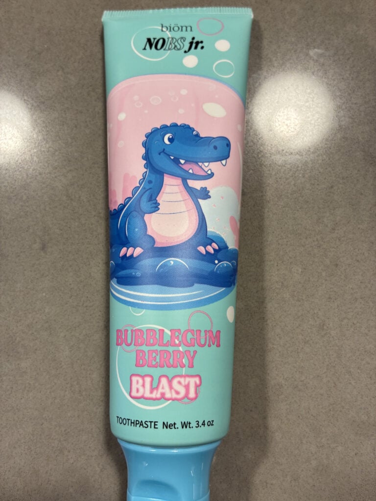A tube of Biom No BS Jr. Bubblegum Berry Blast toothpaste featuring a cartoon alligator on the front. Net weight 3.4 oz.